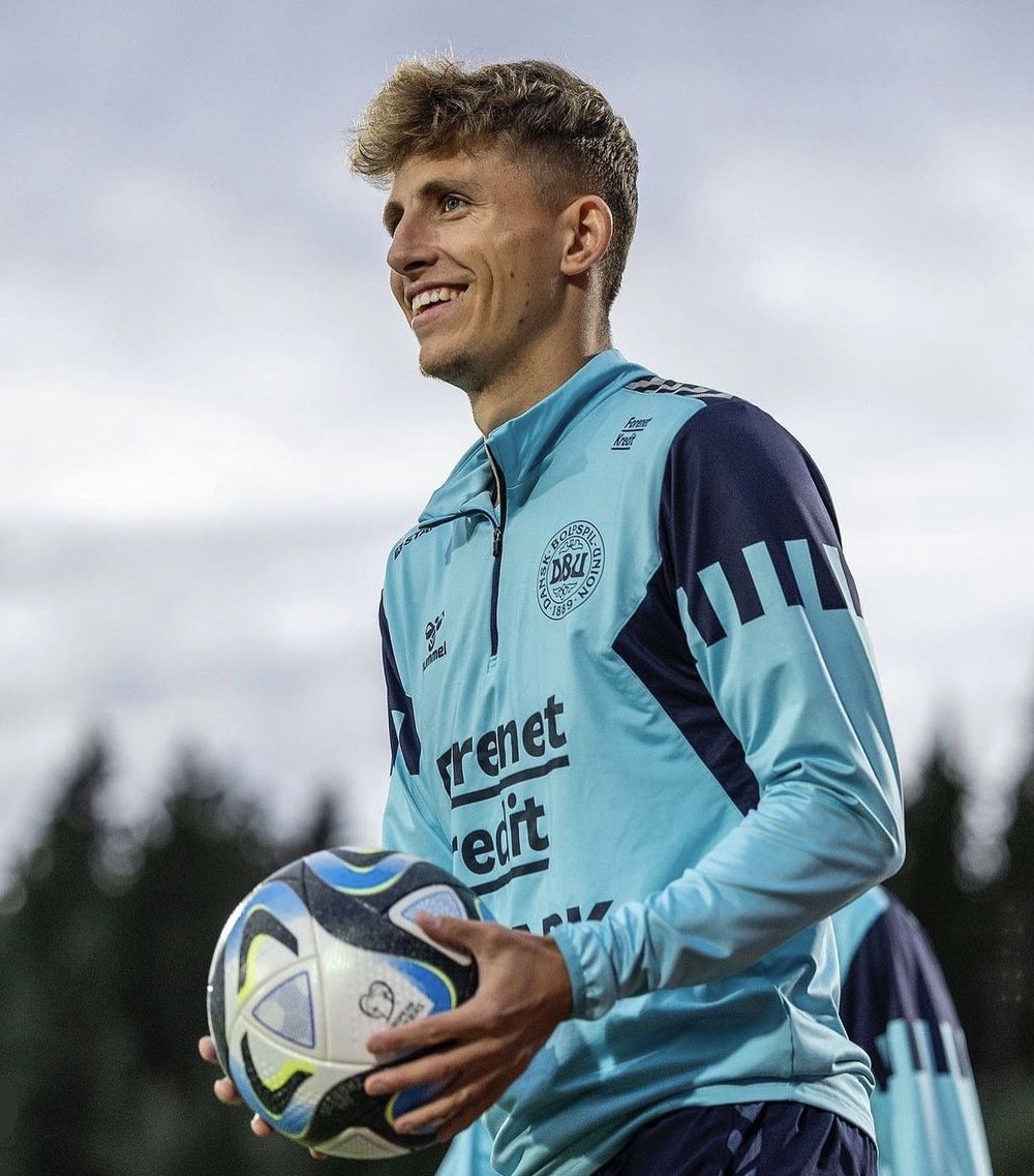 Football player on the Denmark national team in training, holding a ball.